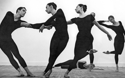 Image: Detail of a black and white photograph by Robert Rauschenberg featuring five dancers from Merce Cunningham's company in various stages of movement wearing all black.