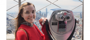 Photo of Mary-kate Grohoski with a viewmaster, high on a city skyscraper